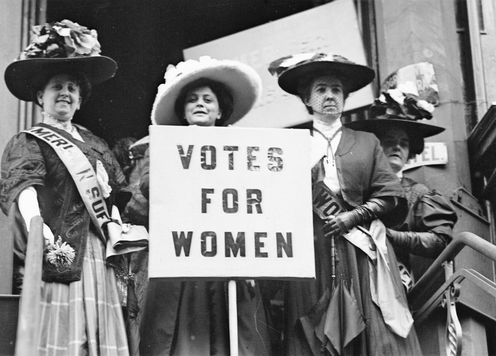 Suffragists holding a Votes for Women sign